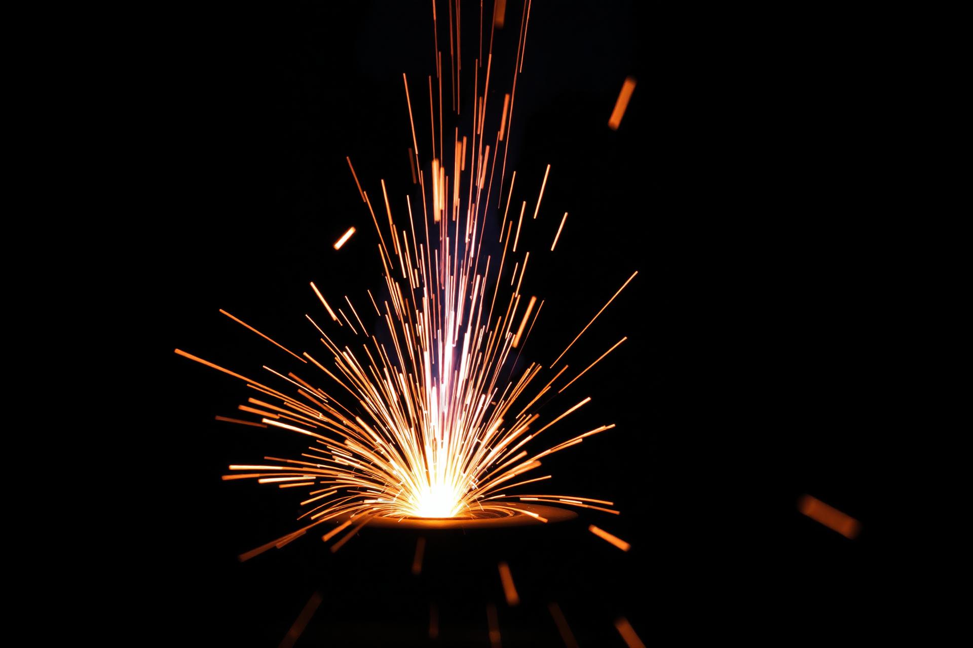 Molten metal weld arc casting sparks in a dark workshop